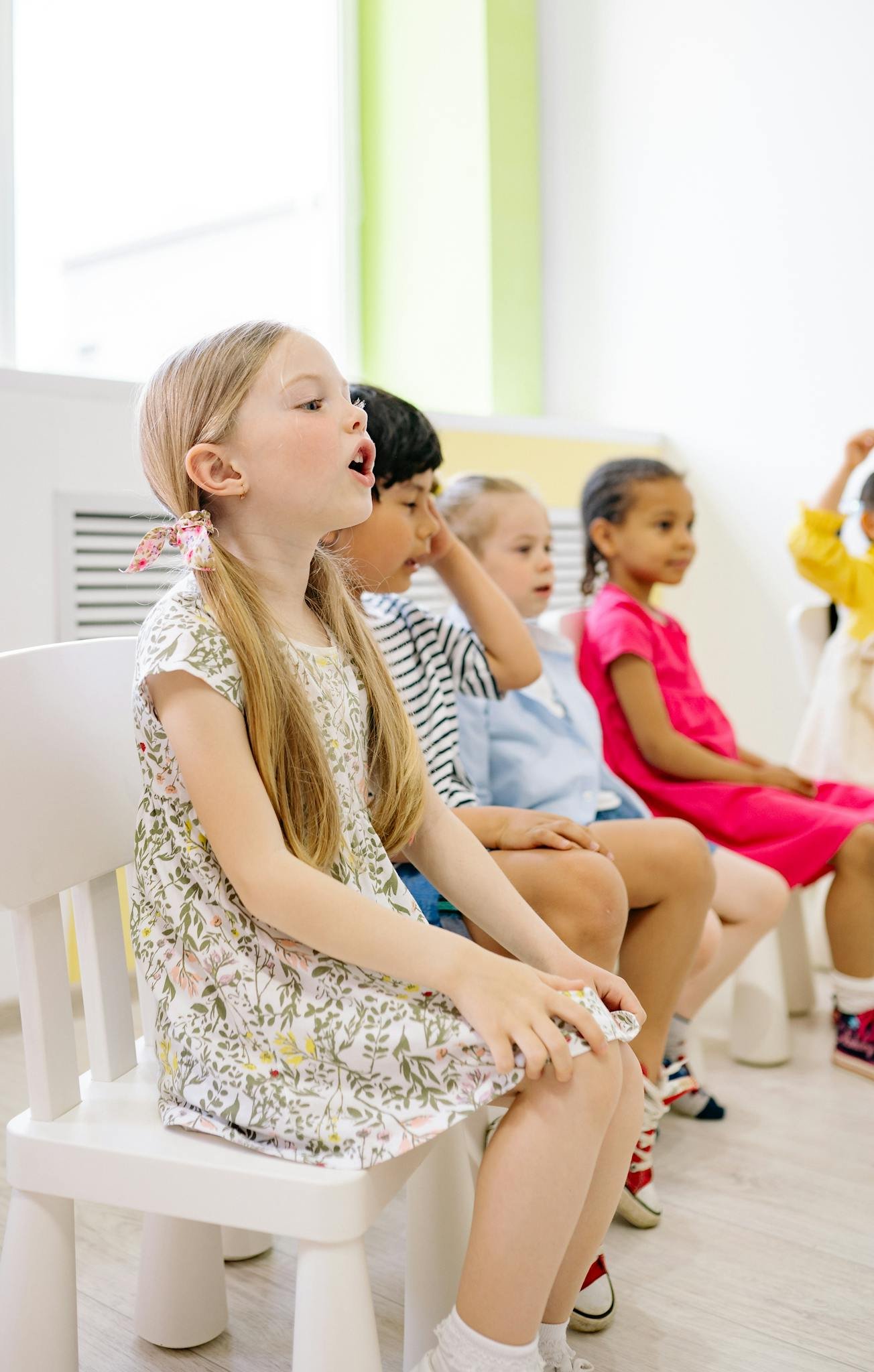 Young children of diverse backgrounds engaging in a fun classroom activity, seated together inside a bright room.